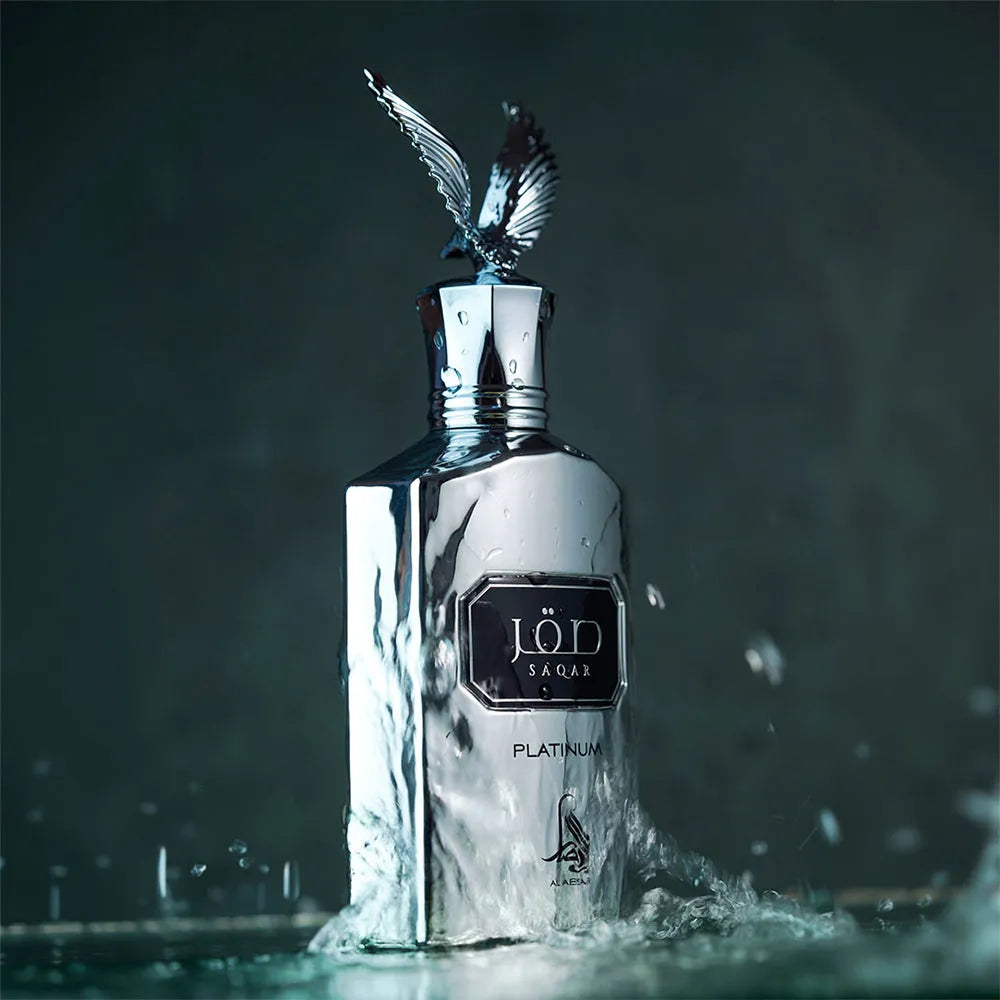 A luxurious 100ml bottle of SAQAR PLATINUM | AL ABSAR Eau de Parfum, with a silver label and a feathered cap, set against a smoky background.